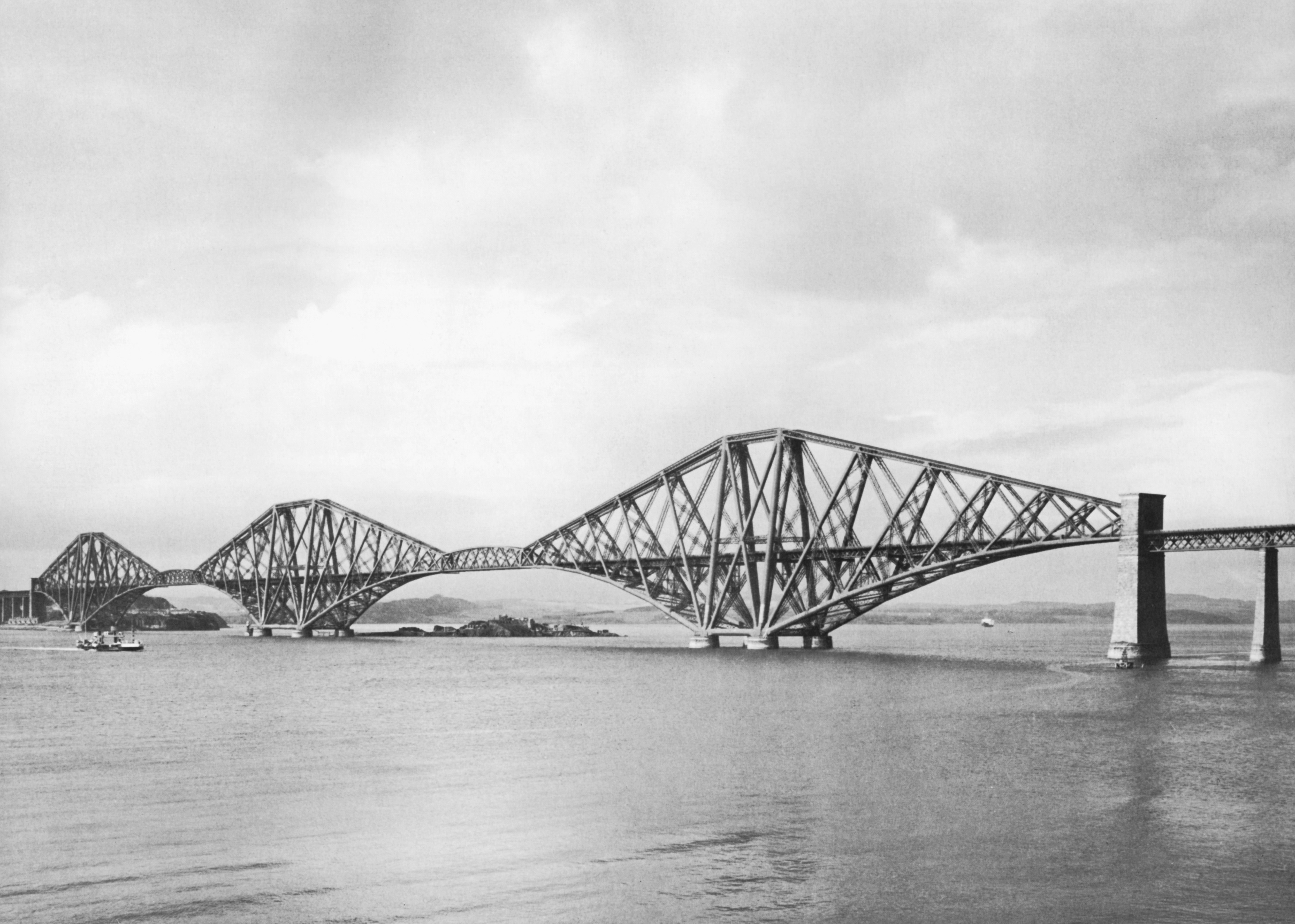 Black and white image of bridge from 1890s, showing small boat about to pass underneath the bridge.