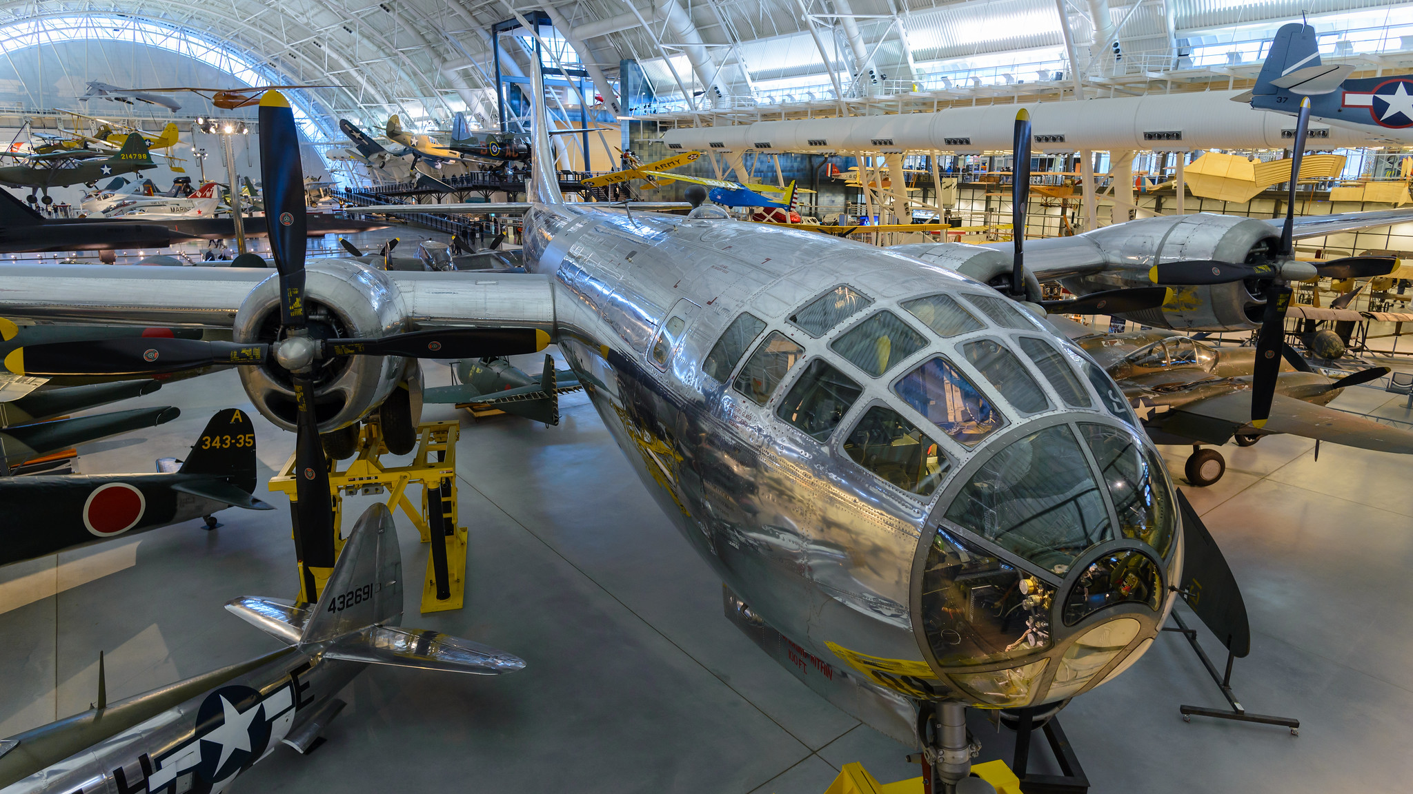 Color Photograph of a large, silver-metallic plane in crowded hanger