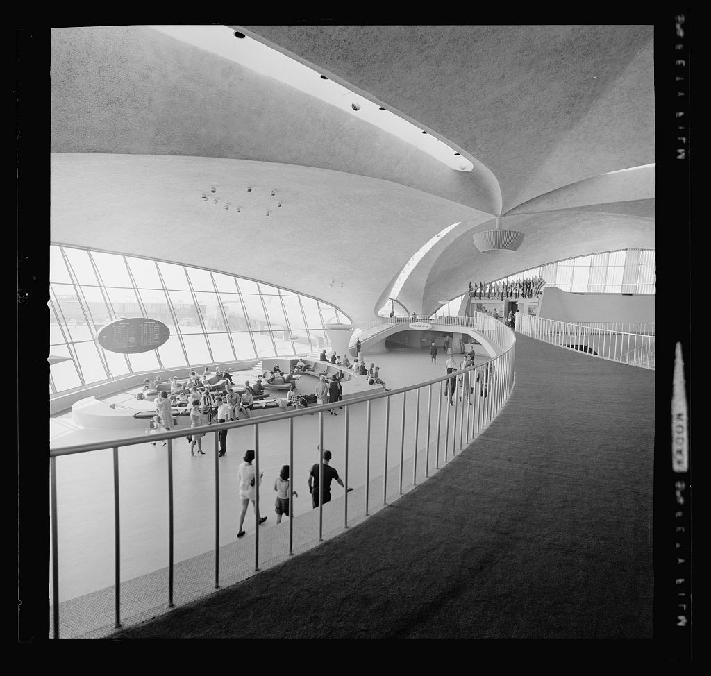 Black and white photograph showing curved walkway and sleek windows and ceiling within the terminal.